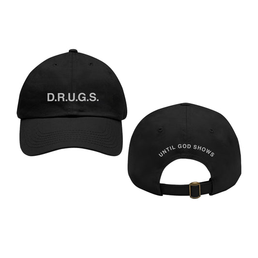 Two black D.R.U.G.S. dad hats shown front and back. The front features "D.R.U.G.S." in white; the back displays "UNTIL GOD SHOWS" above the adjustable strap.