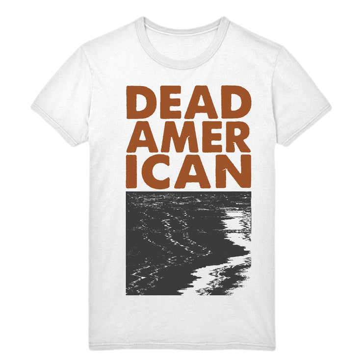 White tshirt against a white background. In a maroon/red text reads "dead american". below that is a black and white graphic of what looks like water, with a glitch effect on it. 