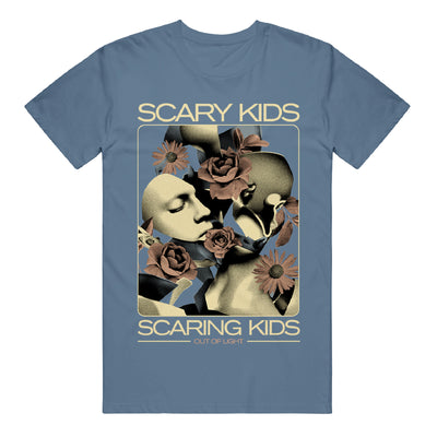 Indigo blue tshirt with a rectangle in the middle. Above the rectangle in pale yellow text says "scary kids". Below the rectangle says "scaring kids". Below that in a pale pink color says "out of light". The rectangle has broken pieces of a porcelain face in a white and grey color. Pale flowers surround the broken pieces.