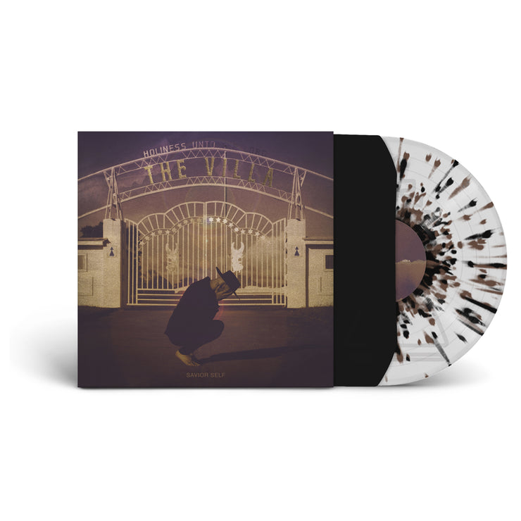 image of the vinyl LP with the vinyl exposed to show color. Color of vinyl is Clear with Brown and Black splatter. Album Cover shows a man crouched down holding his head in his hands out front of an amusement park. 
