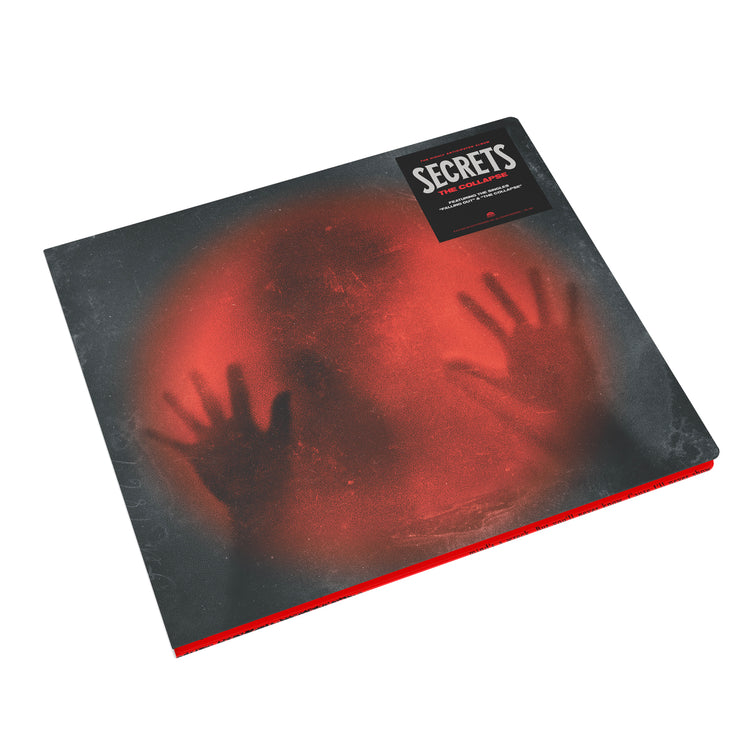 Image of Secrets- the collapse cd case. The album art features a black image with a red lit circle in the center. the silhouette of a head is in the middle, with two hands pressed up against the red light. the hype sticker in the right top corner reads "secrets, the collapse".