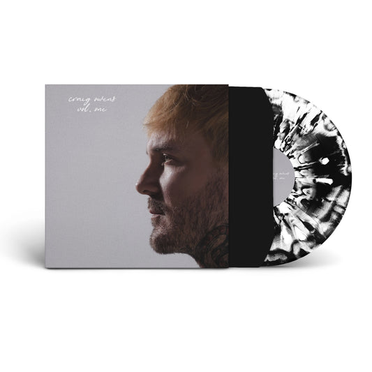 A limited edition Black & White splatter vinyl by Craig Owens slides out of an album cover showing a side profile of a light-haired, tattooed man with the text craig owens vol. one—featuring Cemetery Weather.