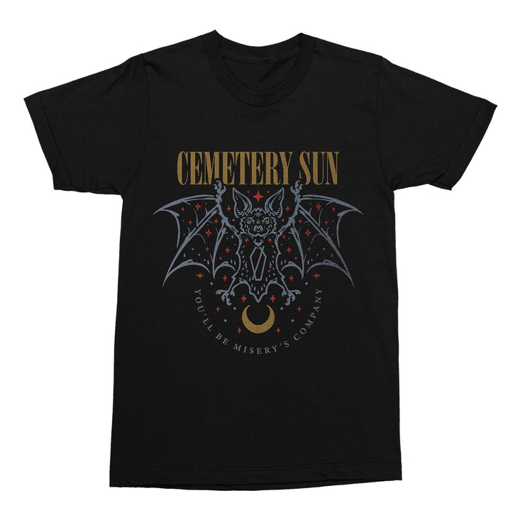 Black tshirt with dark gold text "cemetery sun" across the chest. graphic of a pale blue bat with its wings spread out. Pink stars around its head and a crescent dark gold moon below. The words "you'll be misery's company" are in pale blue and in a horseshoe shape below the bat.